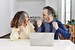 Middle age hispanic couple smiling happy with fists raised up