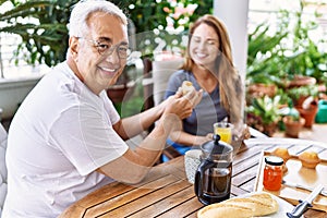 Middle age hispanic couple smiling happy having breakfast at the terrace