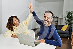 Middle age hispanic couple smiling happy high five