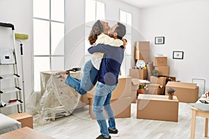 Middle age hispanic couple smiling happy and hugging at new home