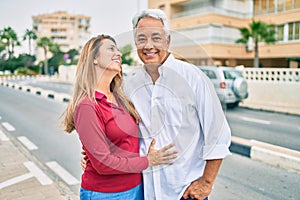 Middle age hispanic couple smiling happy and hugging walking at street