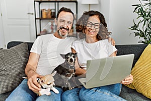 Middle age hispanic couple smiling happy and using laptop