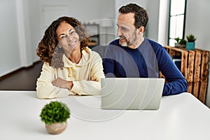 Middle age hispanic couple smiling happy using laptop at home