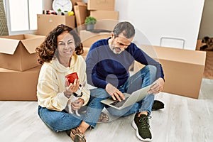 Middle age hispanic couple using laptop and drinking coffee