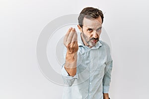 Middle age hispanic man with beard standing over isolated background doing italian gesture with hand and fingers confident