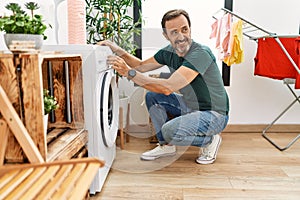 Middle age hispanic man smiling happy doing laundry at home