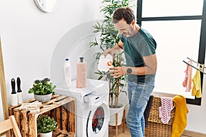 Middle age hispanic man smiling happy doing laundry at home