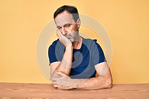 Middle age hispanic man wearing casual clothes sitting on the table thinking looking tired and bored with depression problems with