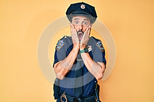 Middle age hispanic man wearing police uniform afraid and shocked, surprise and amazed expression with hands on face