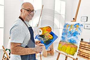 Middle age hispanic painter couple smiling happy painting using paint roller at art studio