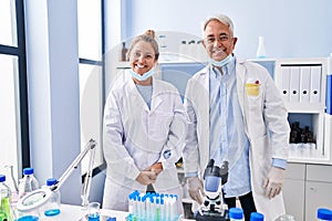 Middle age hispanic people working at scientist laboratory with a happy and cool smile on face