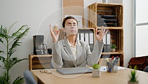 Middle age hispanic woman business worker doing yoga exercise at office