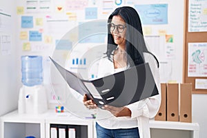 Middle age hispanic woman business worker reading document at office