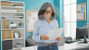 Middle age hispanic woman business worker reading document at the office