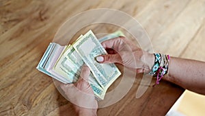 Middle age hispanic woman counting bangladesh taka banknotes at home