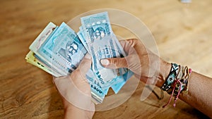 Middle age hispanic woman counting bangladesh taka banknotes at home