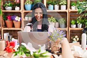 Middle age hispanic woman florist smiling confident using laptop at florist