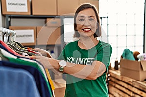 Middle age hispanic woman looking at donated clothes at donations stand