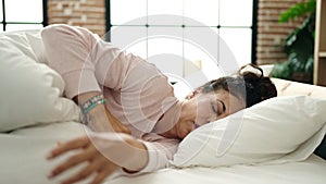 Middle age hispanic woman lying on bed having problem to sleep at bedroom