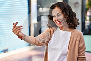 Middle age hispanic woman moving hand asking to come nearer outdoors