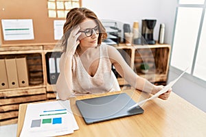 Middle age hispanic woman reading paperwork working at office