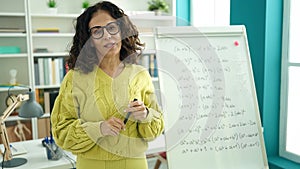 Middle age hispanic woman teacher explaining maths exercise at library university