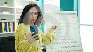 Middle age hispanic woman teacher explaining online maths exercise at library university