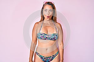 Middle age hispanic woman wearing bikini afraid and shocked with surprise expression, fear and excited face