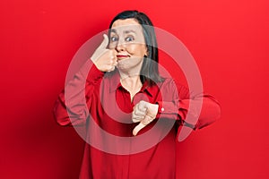 Middle age hispanic woman wearing casual clothes doing thumbs up and down, disagreement and agreement expression