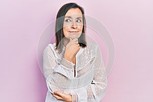 Middle age hispanic woman wearing casual clothes with hand on chin thinking about question, pensive expression