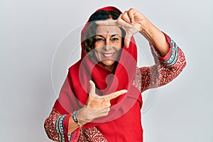 Middle age hispanic woman wearing tradition sherwani saree clothes smiling making frame with hands and fingers with happy face