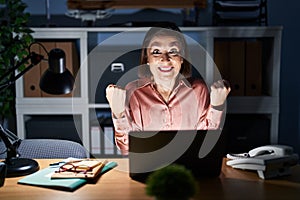 Middle age hispanic woman working using computer laptop late at night screaming proud, celebrating victory and success very
