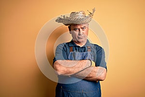 Middle age hoary farmer man wearing apron and hat over isolated yellow background skeptic and nervous, disapproving expression on