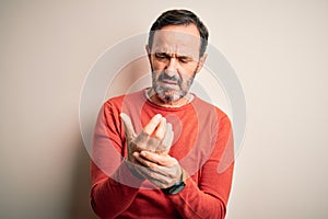 Middle age hoary man wearing casual orange sweater standing over isolated white background Suffering pain on hands and fingers,