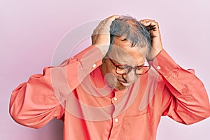 Middle age indian man wearing casual clothes and glasses suffering from headache desperate and stressed because pain and migraine
