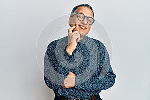 Middle age indian man wearing casual clothes and glasses thinking concentrated about doubt with finger on chin and looking up
