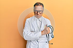 Middle age indian man wearing doctor coat holding stethoscope skeptic and nervous, frowning upset because of problem