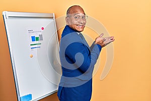 Middle age latin man wearing business clothes on chart presentation pointing aside with hands open palms showing copy space,