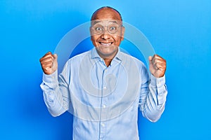 Middle age latin man wearing casual clothes and glasses celebrating surprised and amazed for success with arms raised and open