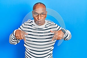 Middle age latin man wearing casual clothes and glasses pointing down with fingers showing advertisement, surprised face and open