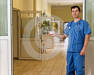 Middle age male doctor in blue scrubs with stethoscope holding White Card