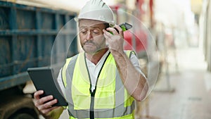 Middle age man architect listening voice message by smartphone using touchpad at street