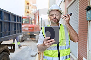 Middle age man architect listening voice message by smartphone using touchpad at street