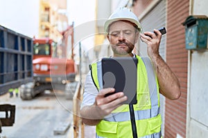 Middle age man architect listening voice message by smartphone using touchpad at street