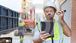 Middle age man architect listening voice message by smartphone using touchpad at street
