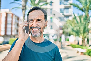 Middle age man with beard smiling happy outdoors speaking on the phone