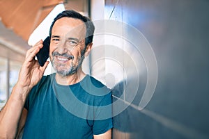 Middle age man with beard smiling happy outdoors speaking on the phone