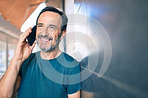 Middle age man with beard smiling happy outdoors speaking on the phone
