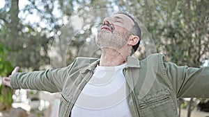 Middle age man breathing with arms open at park