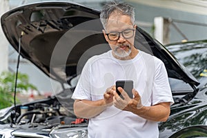 Middle age man with broken down car looking for the phone number for roadside assistant